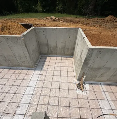 Poured concrete foundation walls around a floor of vapor barrier and steel mesh, ready for the slab