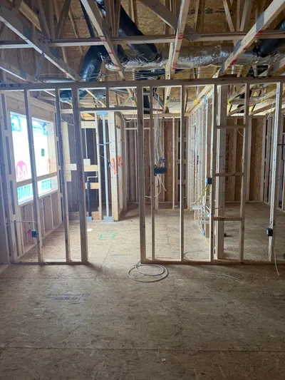 Inside the framed home: open stud walls with device boxes and cable in place, and ductwork run through the floor trusses overhead