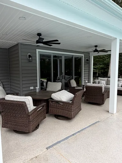 The covered patio: a white beadboard ceiling with two black ceiling fans and recessed lights, over wicker seating and a wall of sliding glass